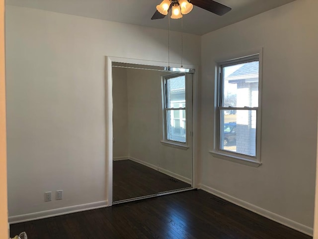 unfurnished dining area with ceiling fan, visible vents, baseboards, and dark wood finished floors