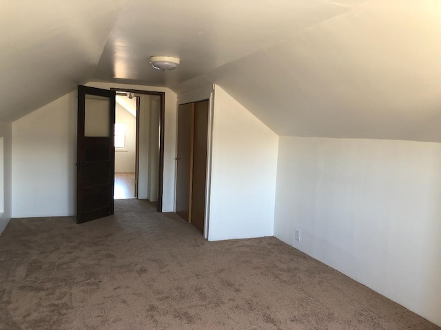 bonus room with lofted ceiling and carpet flooring