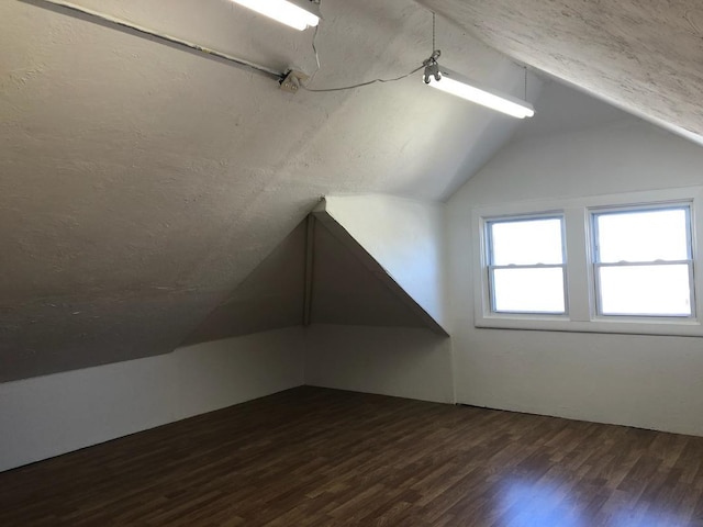 additional living space featuring vaulted ceiling and dark wood finished floors