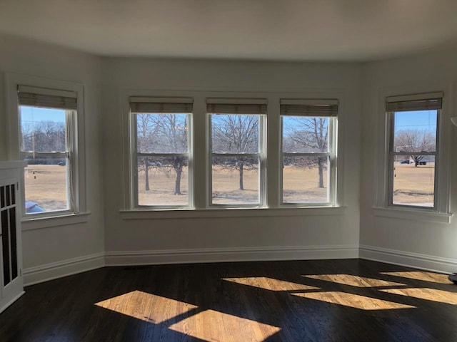 spare room with dark wood-type flooring and baseboards