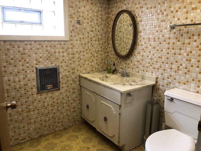 bathroom featuring toilet, tile walls, and vanity