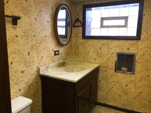 half bath with toilet, wallpapered walls, and vanity