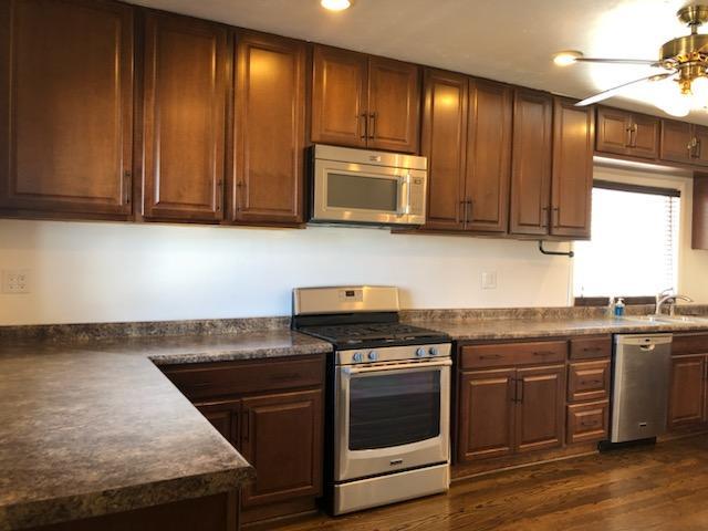 kitchen with ceiling fan, recessed lighting, appliances with stainless steel finishes, dark wood-style floors, and dark countertops