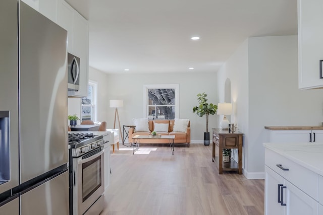 kitchen with white cabinets, light stone countertops, stainless steel appliances, light wood-style floors, and recessed lighting