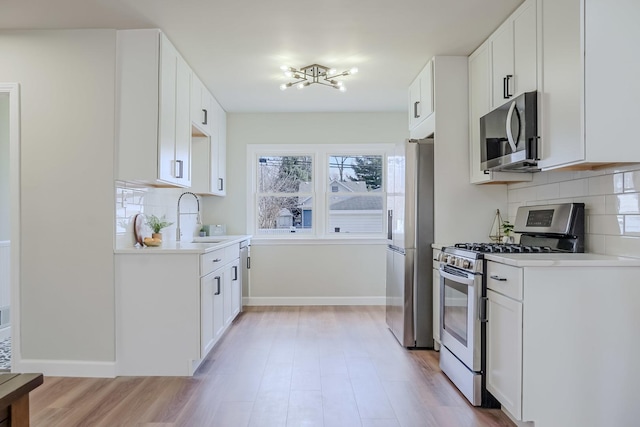 kitchen with stainless steel appliances, light countertops, a sink, and baseboards