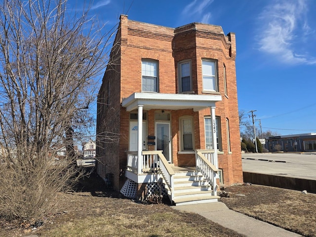 view of property with a porch and brick siding