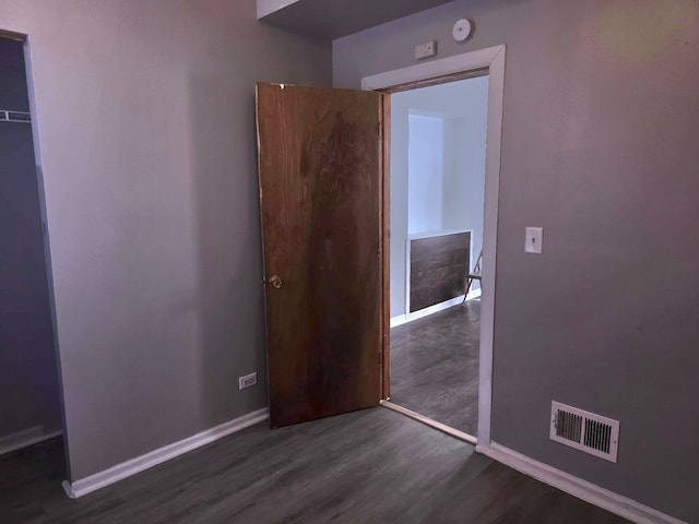 interior space featuring dark wood-style flooring, a closet, visible vents, and baseboards