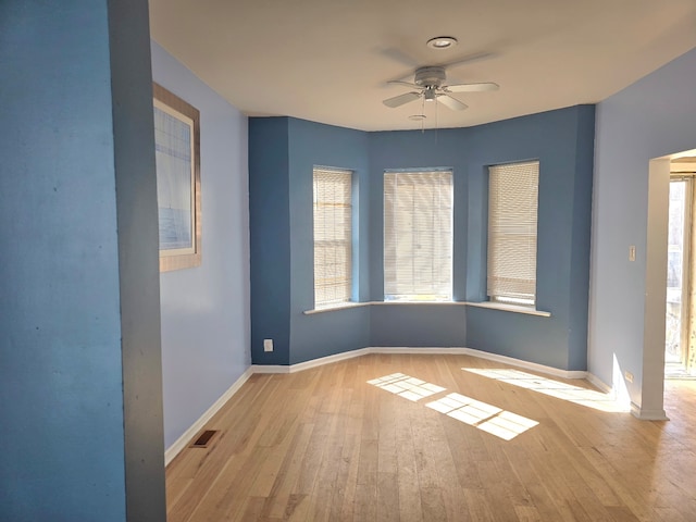 spare room with visible vents, ceiling fan, baseboards, and wood finished floors