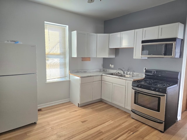 kitchen with stainless steel appliances, a wealth of natural light, a sink, and light wood finished floors