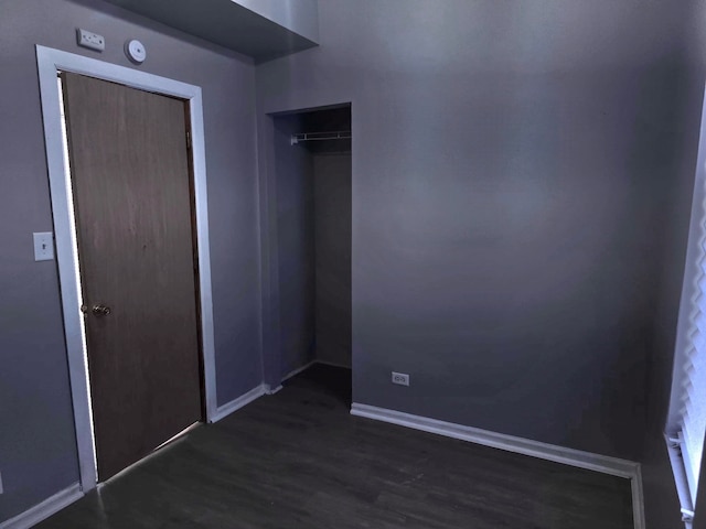 unfurnished bedroom with baseboards and dark wood-type flooring