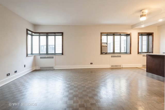 unfurnished room featuring ceiling fan, radiator, baseboards, and a healthy amount of sunlight