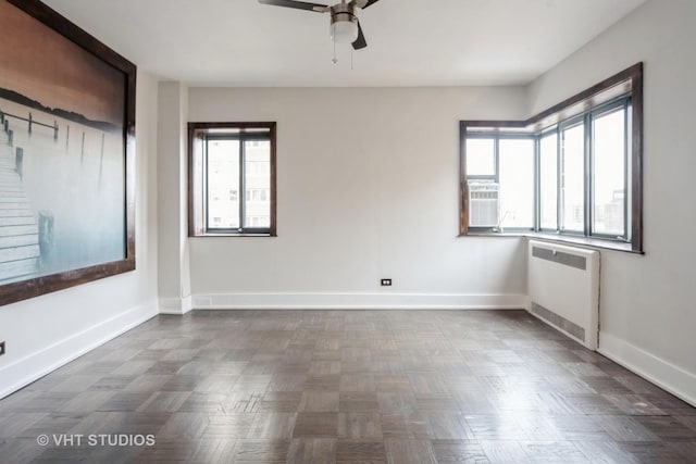 empty room featuring baseboards, a ceiling fan, and radiator