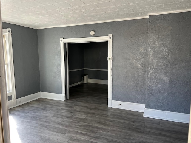 empty room with baseboards, dark wood-style floors, and crown molding