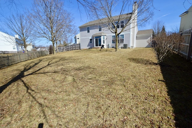 back of house featuring a fenced backyard, a chimney, and a yard