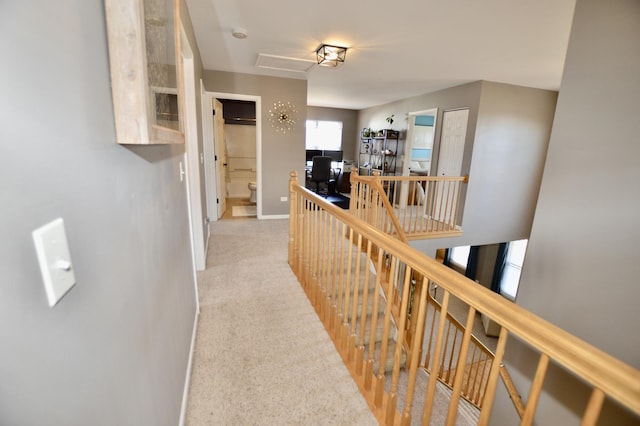 hallway featuring carpet flooring, an upstairs landing, and baseboards