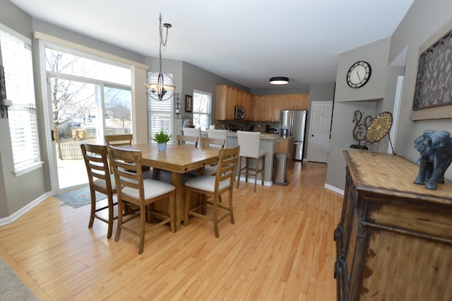 dining area featuring an inviting chandelier, light wood-style flooring, and baseboards