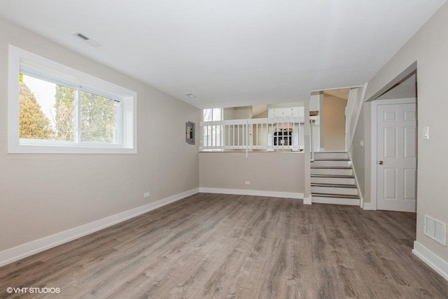 spare room featuring baseboards, stairs, visible vents, and wood finished floors