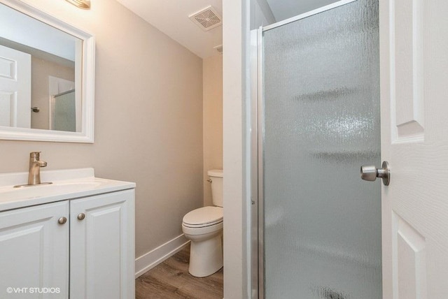 full bathroom with visible vents, toilet, a shower stall, vanity, and wood finished floors