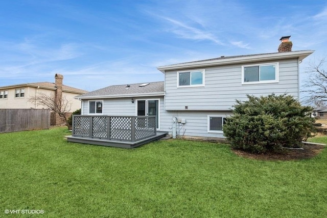 back of house with a chimney, fence, a lawn, and a wooden deck