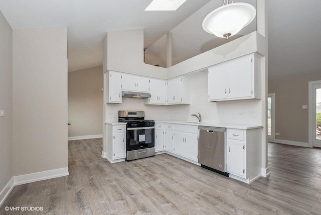 kitchen with a skylight, stainless steel appliances, light countertops, white cabinets, and under cabinet range hood