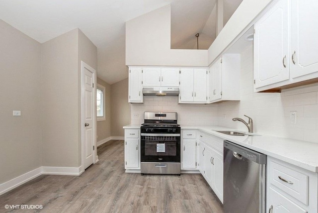 kitchen featuring under cabinet range hood, stainless steel appliances, a sink, white cabinets, and backsplash