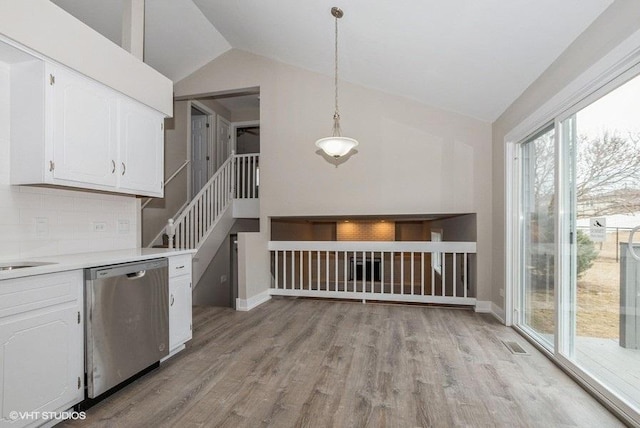 kitchen with dishwasher, light wood-style flooring, vaulted ceiling, light countertops, and white cabinetry