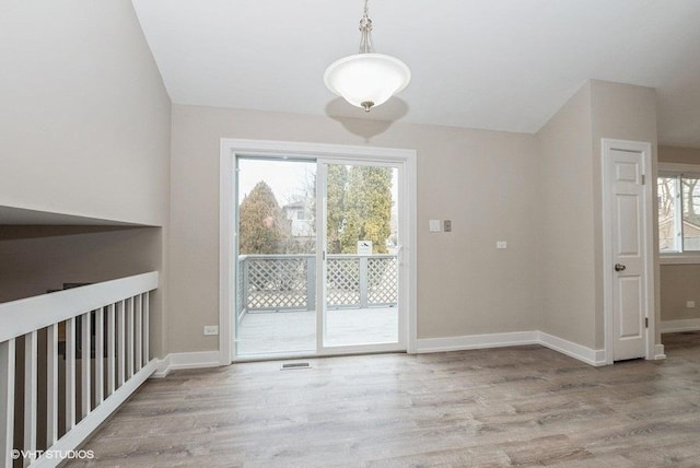 unfurnished dining area featuring plenty of natural light, wood finished floors, and baseboards