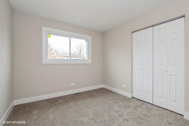 unfurnished bedroom with carpet, a closet, visible vents, and baseboards