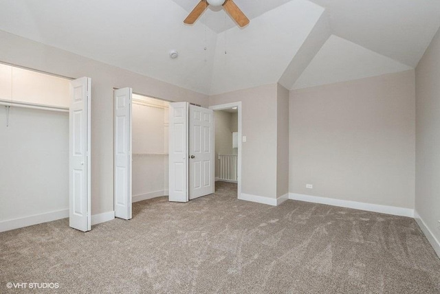 unfurnished bedroom featuring ceiling fan, carpet flooring, baseboards, vaulted ceiling, and two closets