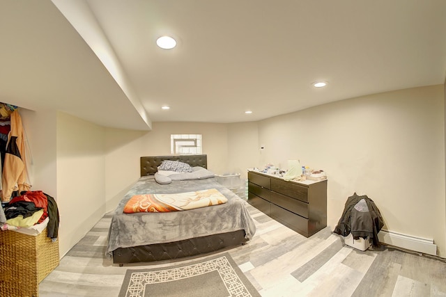 bedroom featuring a baseboard radiator, wood finished floors, and recessed lighting