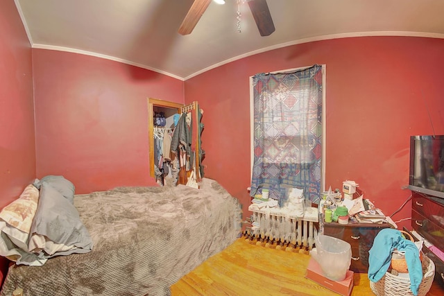 bedroom with wood finished floors, ceiling fan, and ornamental molding