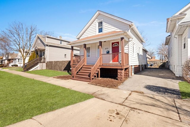 view of front of property featuring driveway, covered porch, stairway, and a front lawn