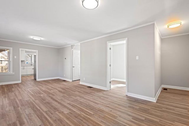 interior space featuring ornamental molding, light wood-style flooring, and baseboards