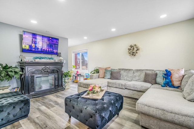 living room featuring recessed lighting, wood finished floors, and a glass covered fireplace