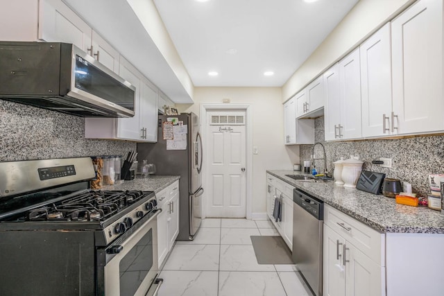 kitchen with stainless steel appliances, a sink, white cabinets, marble finish floor, and tasteful backsplash