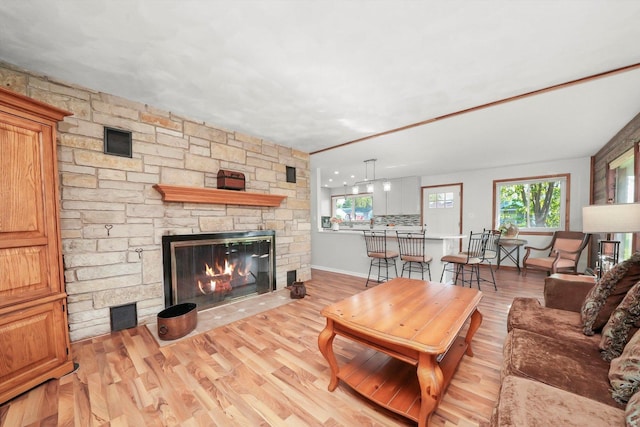 living area featuring a stone fireplace, wood finished floors, and baseboards