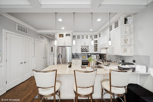 kitchen featuring visible vents, dark wood finished floors, a peninsula, stainless steel appliances, and backsplash