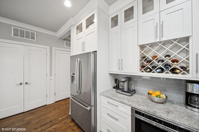 kitchen with white cabinetry, stainless steel fridge, visible vents, and light stone countertops