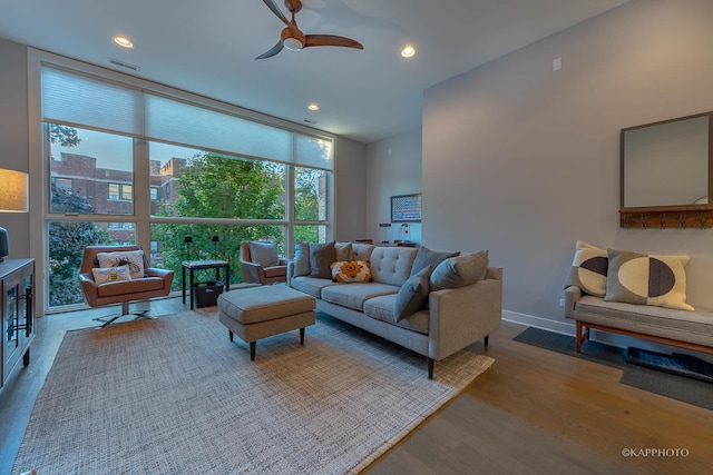 living area with baseboards, visible vents, a ceiling fan, wood finished floors, and a wall of windows