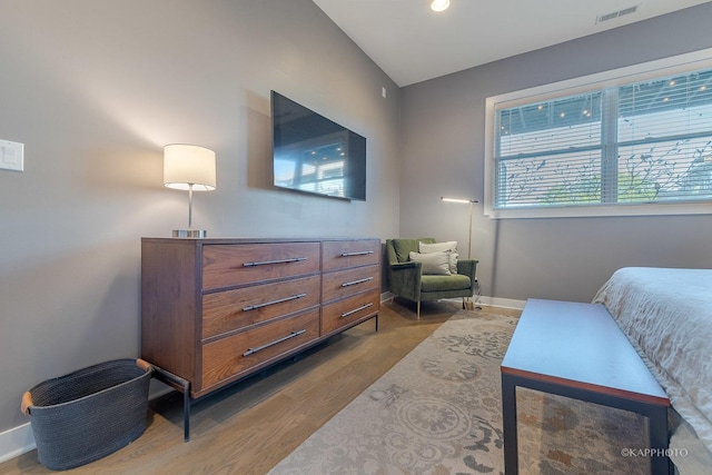 bedroom with baseboards, visible vents, and wood finished floors