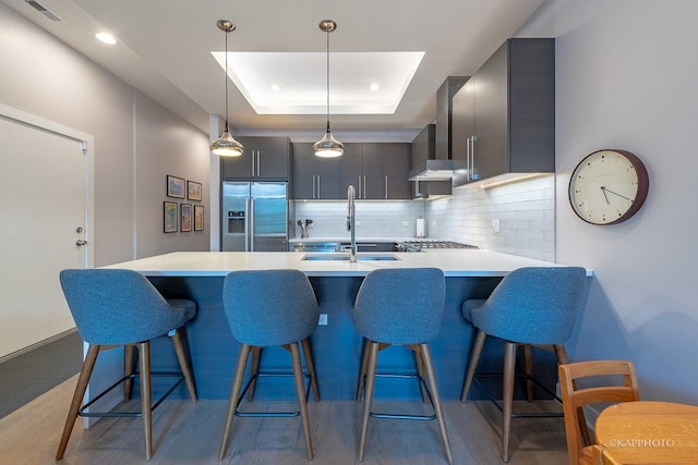 kitchen with light countertops, stainless steel appliances, a sink, and a raised ceiling