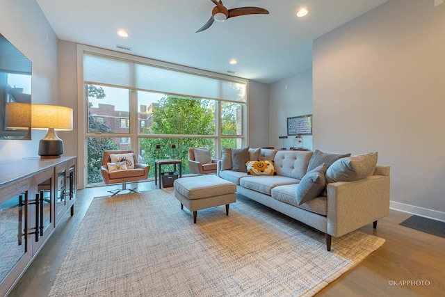 living room with baseboards, a ceiling fan, wood finished floors, a wall of windows, and recessed lighting