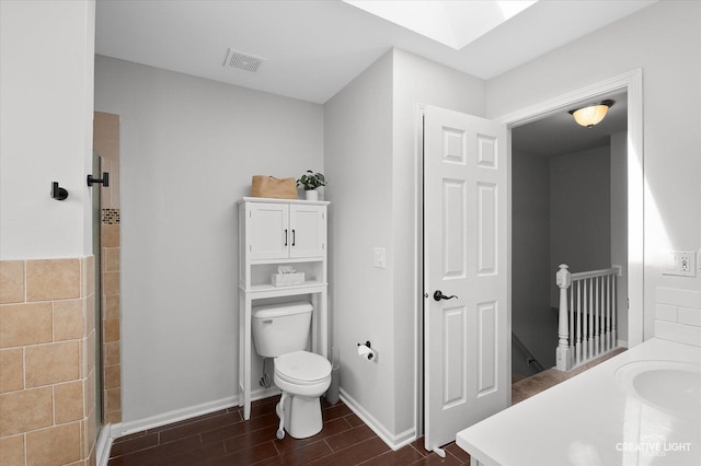 full bath with visible vents, wood tiled floor, toilet, a skylight, and a sink