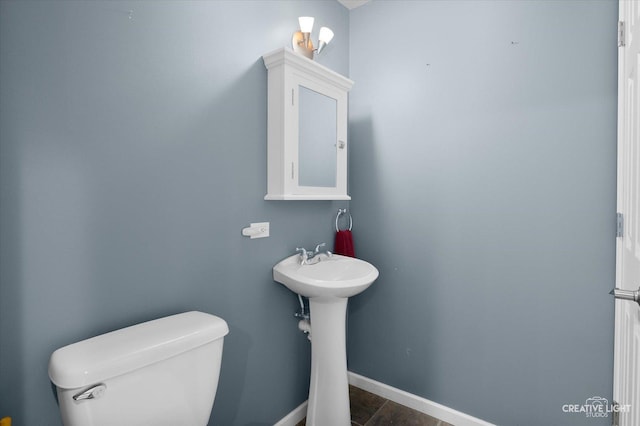 bathroom with toilet, baseboards, and a sink