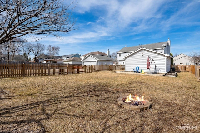 view of yard with a residential view, a fenced backyard, and an outdoor fire pit