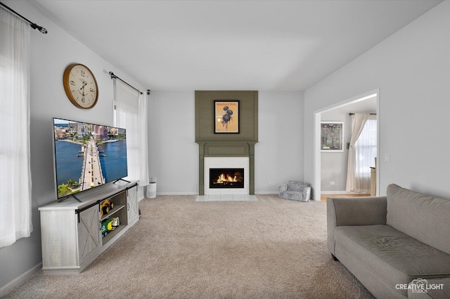 carpeted living area with a fireplace and baseboards