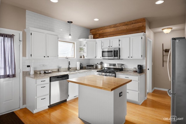 kitchen featuring a sink, stainless steel appliances, white cabinets, tasteful backsplash, and butcher block counters