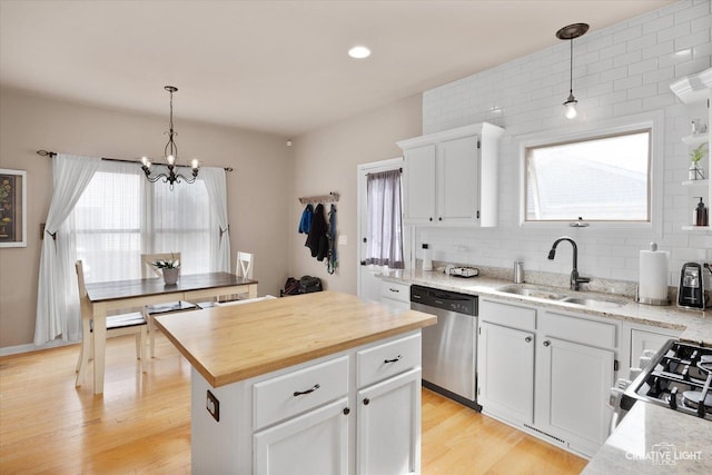 kitchen featuring tasteful backsplash, wooden counters, light wood-type flooring, stainless steel appliances, and a sink