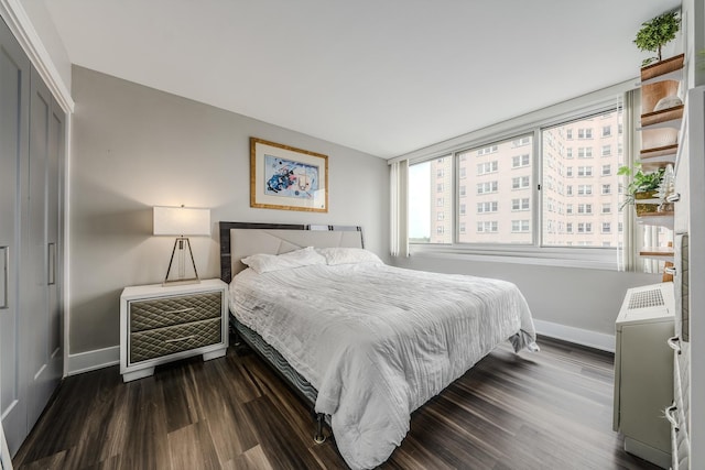 bedroom with a closet, baseboards, and dark wood-style flooring