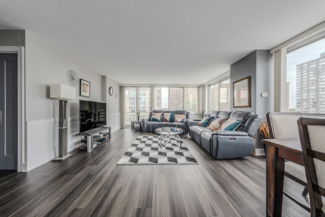 living room featuring wainscoting, plenty of natural light, floor to ceiling windows, and dark wood-style flooring